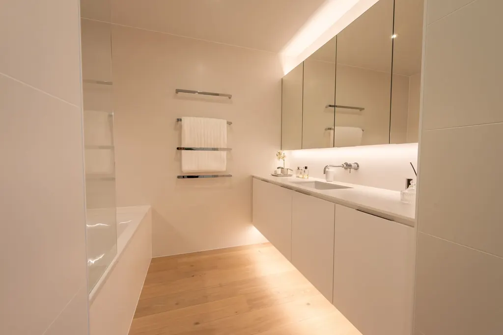White wall-hung vanity with a softly lit plinth and mirrored cabinets