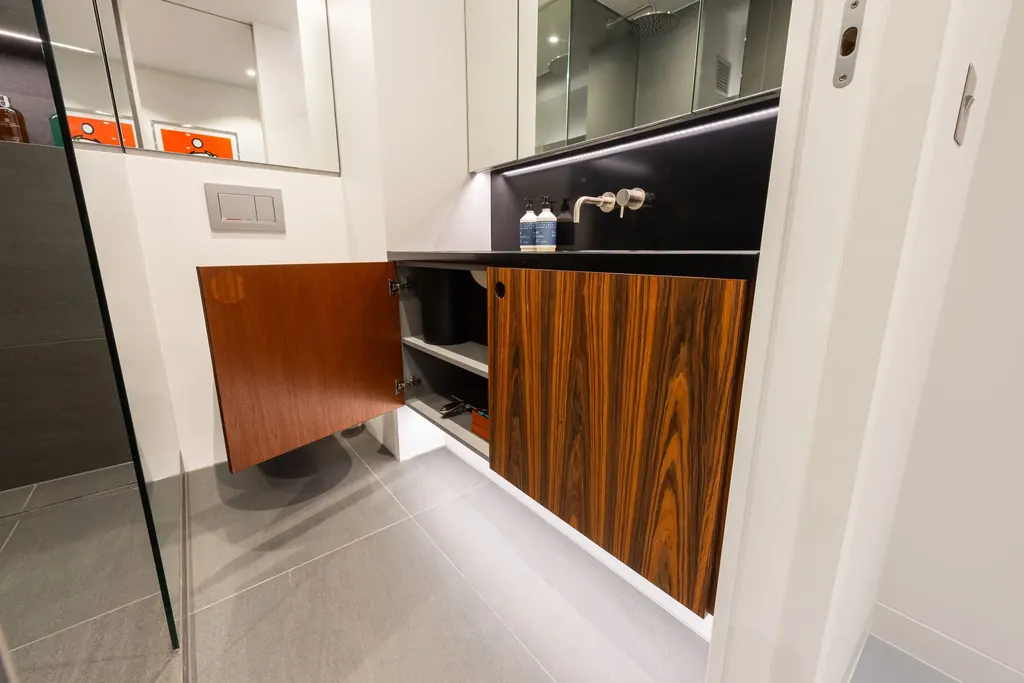 Wall-hung vanity unit in rosewood veneer with a door open