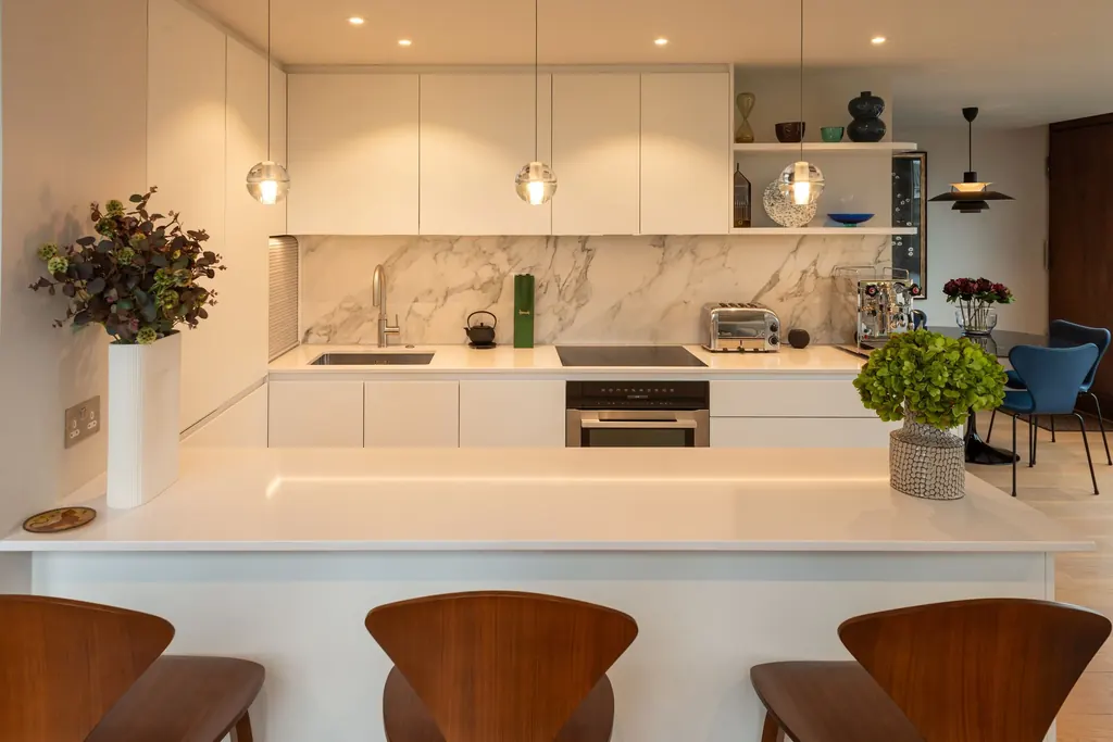 Open-plan kitchen with a marble splashback and a peninsula with walnut stools